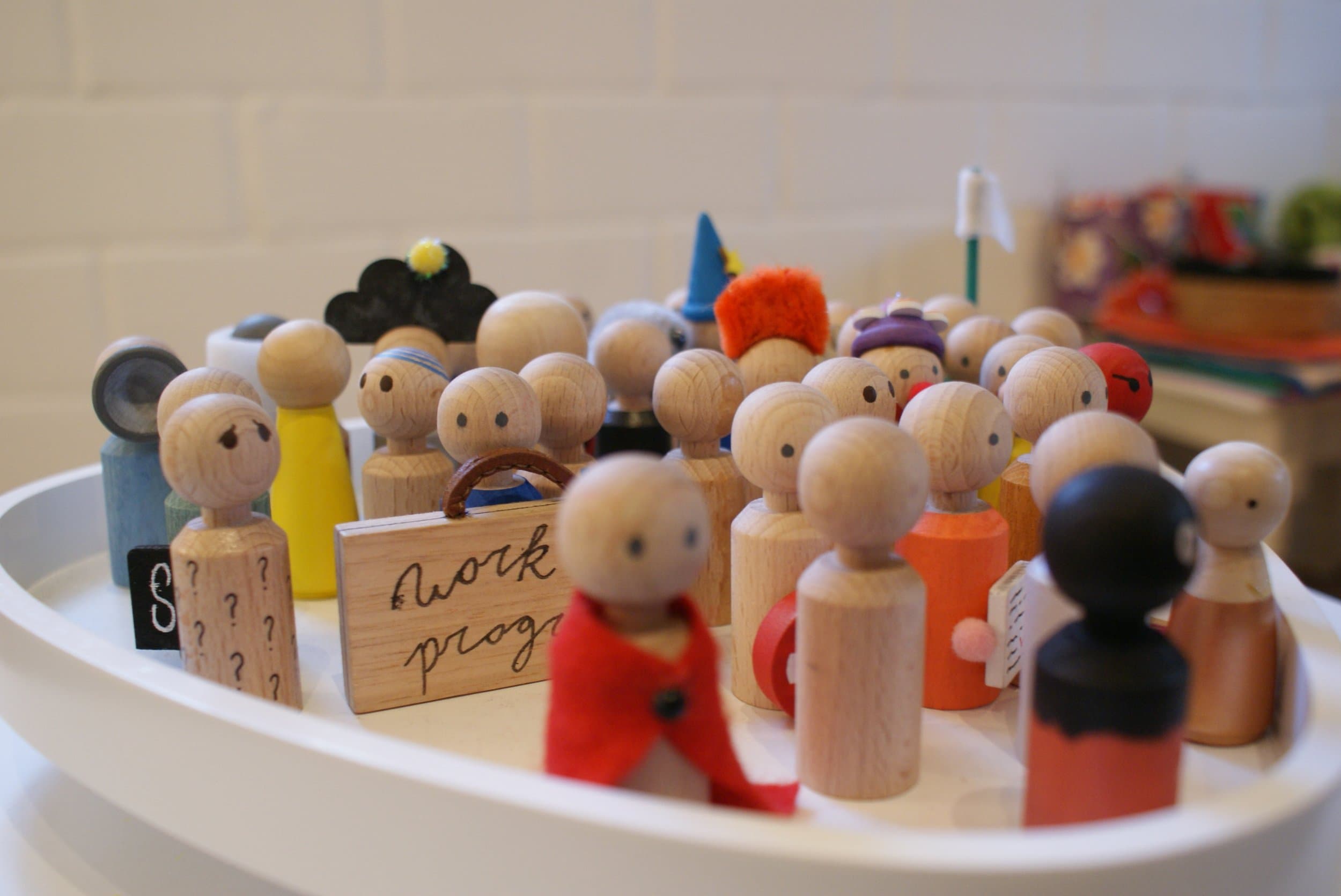 Verschillende kleine houte popjes die verschillende kleren aanhebben